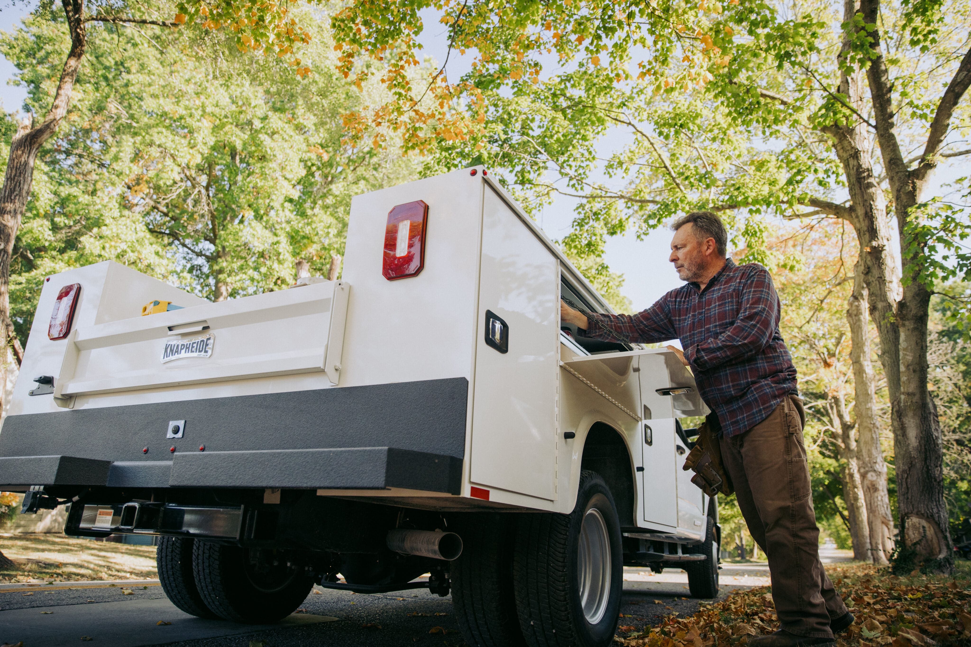 Male Worker Grabbing Cargo from Knapheide Service Truck Compartment
