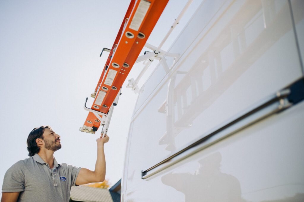 Male Worker Operating Drop Down Ladder Rack on Knapheide Upfitted Cargo Van