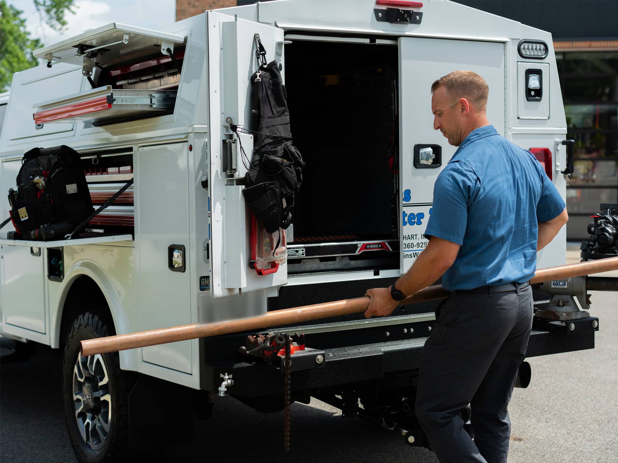 awkins-water-tech-enclosed-service-truck-field-technician-pulling-pipe-from-cargo-area