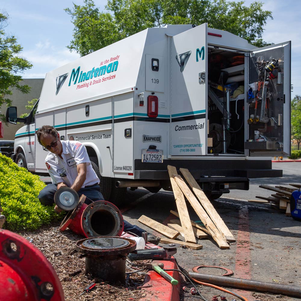 minuteman-plumbing-and-drain-services-worker-and-knapheide-kuv-van-on-jobsite