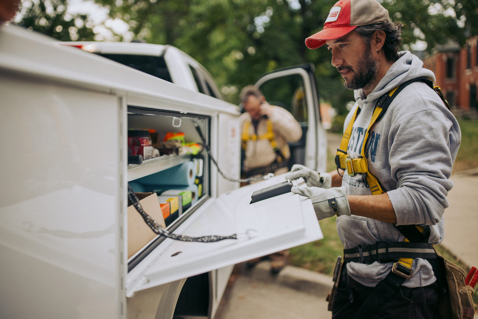 Male Worker Opening Knapheide Service Truck Compartment With Supervisor Using Cellphone In Background