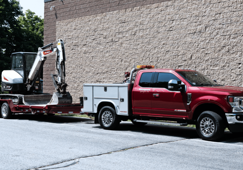 Monsignore Excavating service truck hooked up to a trailer with an excavator.